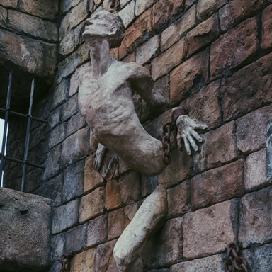 Stone sculpture figure emerging from a rough brick wall